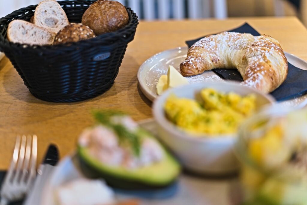A basket of bread and a croissant with butter.